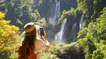 A woman taking a picture of a waterfall